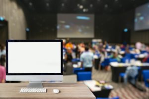 Blank White Laptop Screen with Blurred Event Crowd and Big Screen